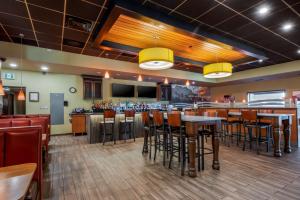 a restaurant with a bar with tables and stools at Best Western Plus Chateau Fort St. John in Fort Saint John