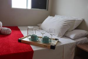 a tray with cups and glasses on a bed at Lindo Flat Verde Mar em São José da Coroa Grande, Pernambuco in São José da Coroa Grande