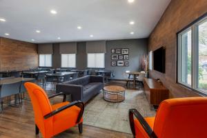 a lobby with orange chairs and tables and a restaurant at Quality Inn Airport West in Mississauga