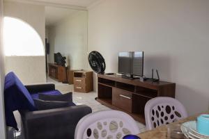 uma sala de estar com uma televisão e um sofá e cadeiras em Lindo Flat Verde Mar em São José da Coroa Grande, Pernambuco em São José da Coroa Grande