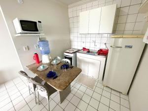 a small kitchen with a table and a refrigerator at Lindo Flat Verde Mar em São José da Coroa Grande, Pernambuco in São José da Coroa Grande