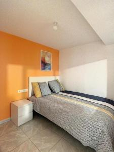 een bed in een kamer met een oranje muur bij GRAND T2 GARE AMIENS TOUT CONFORT 2PERS WIFI in Amiens
