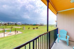 a blue chair sitting on a balcony looking out at a park at Unit 32, Island Retreat Resort in Port Aransas