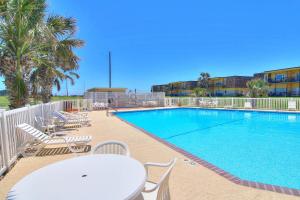 a swimming pool with chairs and a table and a table and chairs at Unit 32, Island Retreat Resort in Port Aransas