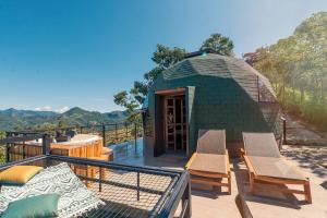 a small green building with chairs on a deck at La Colina Glamping in La Vega