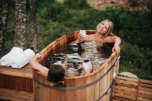 a woman in a hot tub with a woman holding a drink at FlowEdge Riverside Getaway in Meaghers Grant