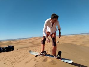 un hombre parado en una patineta en el desierto en Nomad Bivouac, en Merzouga