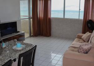 uma sala de estar com um sofá e uma mesa com uma televisão em Lindo Flat Mar Azul em São José da Coroa Grande, Pernambuco em São José da Coroa Grande