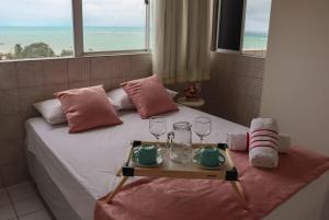 a bed with a tray of glasses and a window at Lindo Flat Mar Azul em São José da Coroa Grande, Pernambuco in São José da Coroa Grande +25 photos