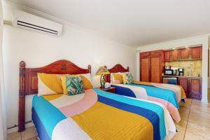 a bedroom with three beds with colorful blankets at Islander on the Beach 171 in Kapaa