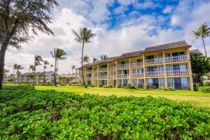 a large building with palm trees and bushes at Islander on the Beach 157 in Kapaa