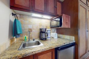 a kitchen counter with a sink and a microwave at Islander on the Beach 211 in Kapaa