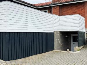 a building with a black fence and a garage at 10 person holiday home in Roslev in Flovtrup