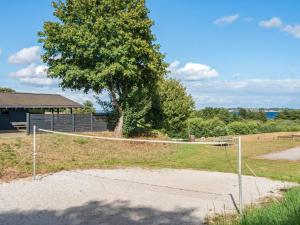 una red de voleibol en un campo con un árbol en 7 person holiday home in Aabenraa, en Aabenraa
