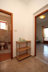 a bathroom with a toilet and a wooden shelf at Apartments by the sea Kraj, Pasman - 8247 in Tkon