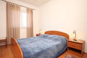 a bedroom with a bed with a blue blanket on it at Apartments by the sea Kraj, Pasman - 8247 in Tkon
