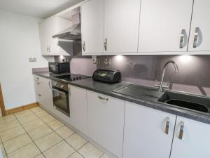 a kitchen with white cabinets and a sink at Bridgeway House in Blaenau-Ffestiniog