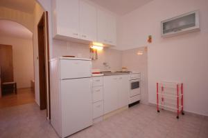 una cucina con armadietti bianchi e frigorifero bianco di Seaside holiday house Cove Rogacic, Vis - 8889 a Vis