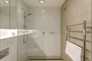 uma casa de banho com uma cabina de duche em vidro e um lavatório. em Lovely One Bedroom + Study with Infinity Pool em Sydney