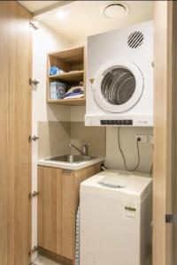 a small kitchen with a washing machine and a sink at Lovely One Bedroom + Study with Infinity Pool in Sydney