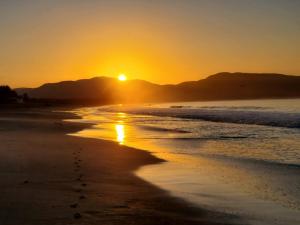 a sunset on the beach with footprints in the sand at Casa Punta Perula Boutique Hotel in Pérula +10 photos