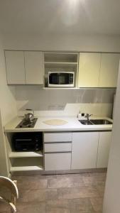 a small kitchen with a sink and a microwave at Delicado loft amplio y de diseño in Rosario