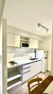 cocina con armarios blancos y nevera blanca en Delicado loft amplio y de diseño en Rosario