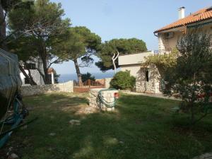 a yard with a house and a fence and trees at Apartments by the sea Mali Losinj (Losinj) - 2485 in Mali Lošinj