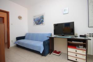 a living room with a blue couch and a tv at Apartments by the sea Mali Losinj (Losinj) - 2485 in Mali Lošinj