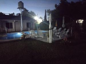 a yard with chairs and a pool at night at Cabañas Midelem in Chascomús