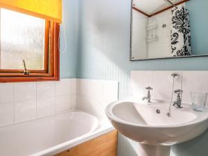 a bathroom with a sink and a tub and a mirror at Lodge Two, Country View Park in Faversham