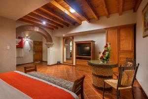 a room with a bed and a table and a television at Hotel la Parroquia in Pátzcuaro