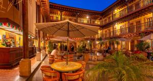 Hotel la Parroquia في باتزكوارو: فناء مع طاولة مع مظلة في مبنى