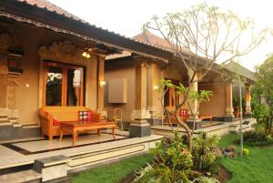 a house with a patio with a table and a bench at Trijaya Guest House Pemuteran in Pemuteran