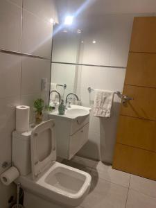 a white bathroom with a toilet and a sink at Pellegrini Apartment Mendoza in Mendoza