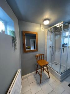 a bathroom with a shower and a wooden chair at Room in family home near Penny Lane Liverpool in Liverpool