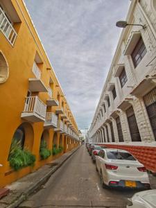 rząd budynków na ulicy z zaparkowanymi samochodami w obiekcie Happy tours apartments w mieście Cartagena de Indias