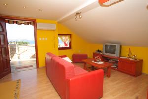 ein Wohnzimmer mit einem roten Sofa und einem TV in der Unterkunft Apartments with a parking space Preko, Ugljan - 8428 in Preko