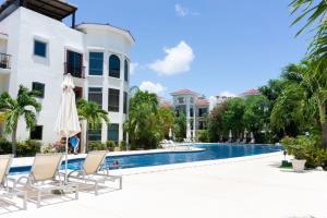 een zwembad in een resort met stoelen en een parasol bij Paseo del Sol Condohotel by BVR in Playa del Carmen