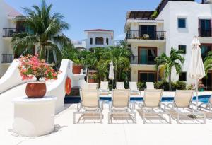 普拉亞德爾卡曼的住宿－Paseo del Sol Condohotel by BVR，一组椅子和遮阳伞,位于游泳池旁