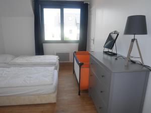 ein Schlafzimmer mit einer Kommode und einem Bett sowie einem Schreibtisch mit einem Computer in der Unterkunft Beachfront Holiday Home, Penmarch-St Guénolé in Penmarcʼh