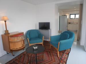 ein Wohnzimmer mit 2 blauen Stühlen und einem Tisch in der Unterkunft Beachfront Holiday Home, Penmarch-St Guénolé in Penmarcʼh
