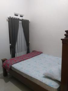 Un dormitorio con una cama y una ventana con cortinas. en Almahyra Homestay Syariah, en Bukittinggi