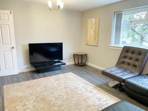 a living room with a couch and a flat screen tv at Cozy Nights - Shawholm Cr in Mansewood