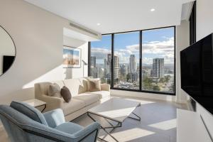 a living room with a couch and chairs and a large window at Meriton Suites Surfers Paradise in Gold Coast
