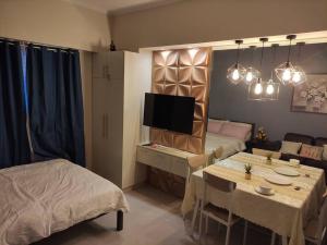 Una sala de estar con una mesa, una cama y un televisor. en Studio U Across SM Cebu with kitchen! sunvida 2407, en Cebú