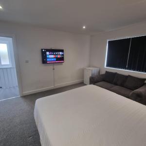Enfield Lock的住宿－4 bed apartment In Enfield north London，一间卧室配有一张床、一张沙发和一台平面电视。