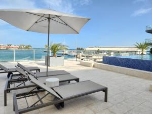 a patio with chairs and an umbrella and a pool at ARUBA DREAM GETAWAY 2BR/2BT OCEAN & POOL VIEW in Oranjestad