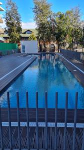 a swimming pool with blue water and a fence at Departamento en pucon in Pucón