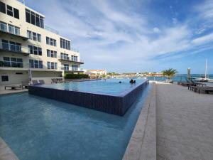 a swimming pool in front of a building at ARUBA DREAM GETAWAY 2BR/2BT OCEAN & POOL VIEW in Oranjestad